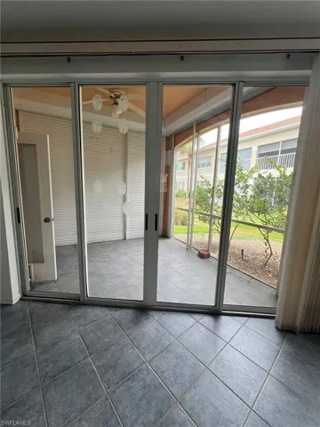 Doorway to outside featuring dark tile patterned floors and a ceiling fan