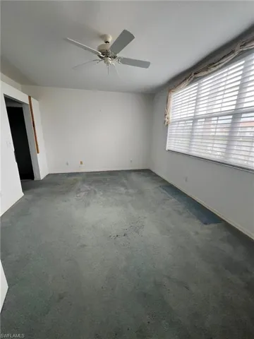 Carpeted spare room with ceiling fan and baseboards
