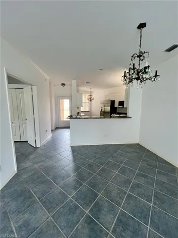 Unfurnished living room featuring a chandelier and dark tile patterned floors