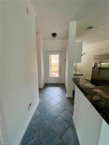 Entryway with dark tile patterned floors and baseboards