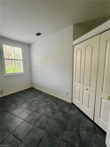 Unfurnished bedroom with a closet and dark tile patterned floors