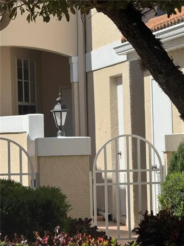 View of side of home with stucco siding and a gate