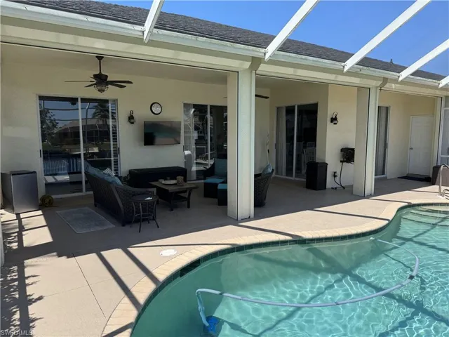 Outdoor pool featuring a patio, outdoor lounge area, glass enclosure, and ceiling fan
