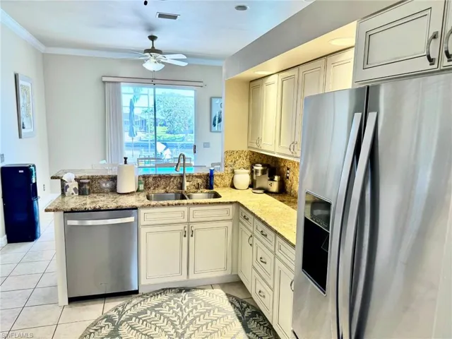 Kitchen with stainless steel appliances, a ceiling fan, light tile patterned floors, a sink, and a peninsula