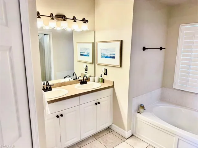 Bathroom with a garden tub, tile patterned floors, a sink, and double vanity