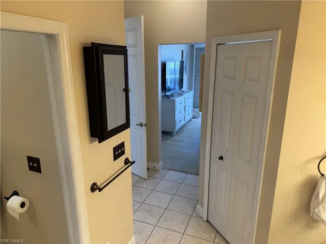 Hallway featuring light carpet, light tile patterned floors, and baseboards