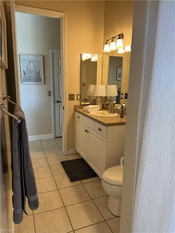 Full bathroom with double vanity, tile patterned floors, a shower with curtain, toilet, and a sink