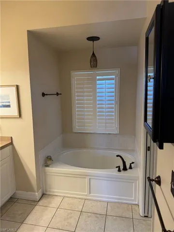 Full bathroom with tile patterned floors, a bath, vanity, and baseboards