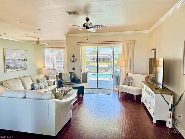 Living room featuring visible vents, crown molding, and ceiling fan