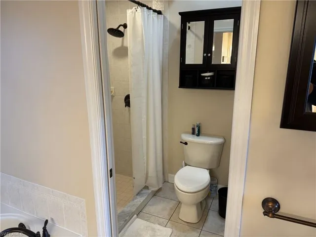 Bathroom featuring toilet, a shower stall, and tile patterned flooring