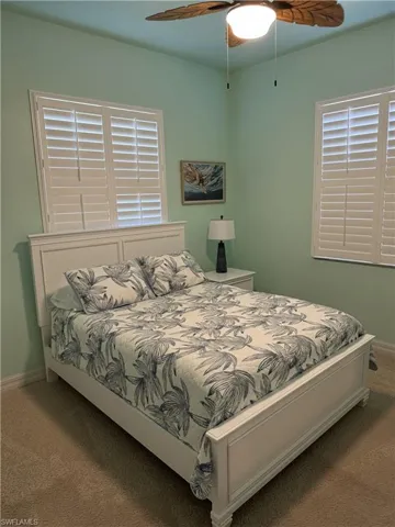 Carpeted bedroom featuring ceiling fan and baseboards