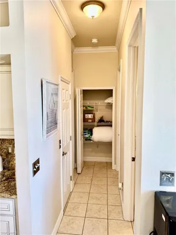 Hallway featuring ornamental molding and light tile patterned floors