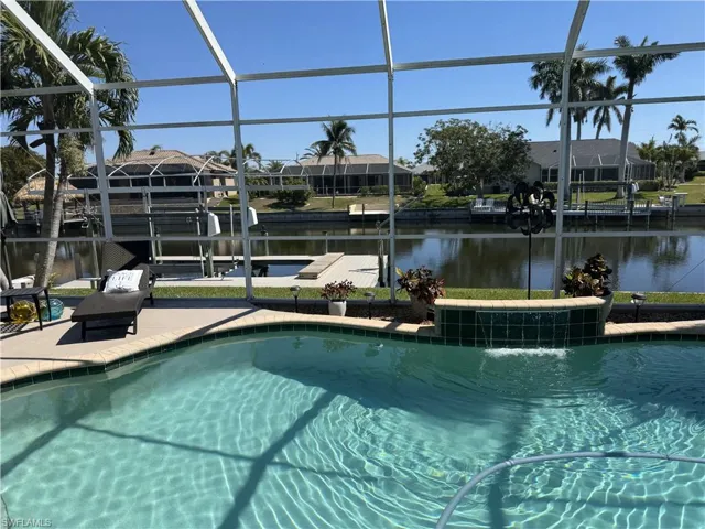 Pool featuring a water view, glass enclosure, a dock, and a patio area