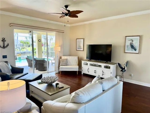 Living room featuring baseboards, a ceiling fan, crown molding, and dark wood-style floors