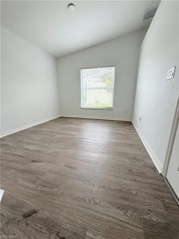 Spare room featuring dark wood-type flooring and baseboards
