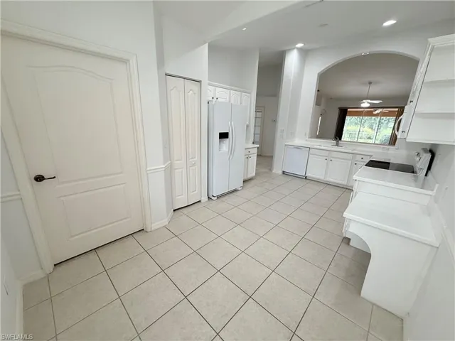 Kitchen featuring white appliances, ceiling fan, light tile patterned floors, arched walkways, and open shelves