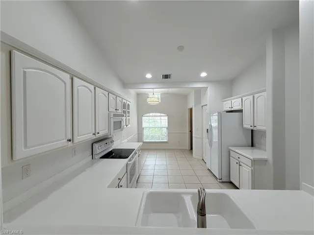 Kitchen featuring white appliances, recessed lighting, white cabinets, light tile patterned floors, and light countertops