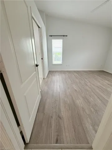 Unfurnished bedroom with light wood finished floors and lofted ceiling