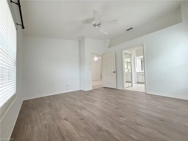 Unfurnished bedroom with wood finished floors, connected bathroom, and a ceiling fan