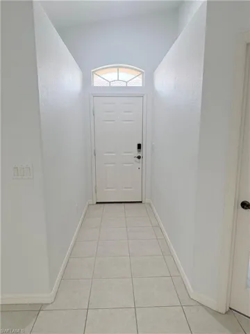 Doorway with light tile patterned floors and baseboards