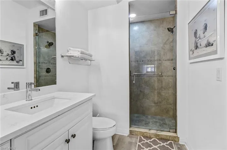 Bathroom featuring hardwood / wood-style floors, vanity, toilet, and an enclosed shower