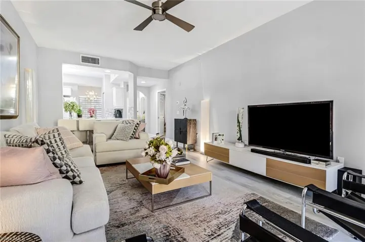 Living room featuring ceiling fan with notable chandelier and hardwood / wood-style floors