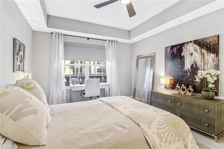 Bedroom with wood-type flooring, a tray ceiling, and ceiling fan