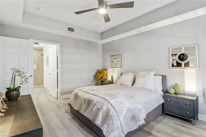Bedroom featuring ceiling fan, light hardwood / wood-style flooring, and ensuite bathroom