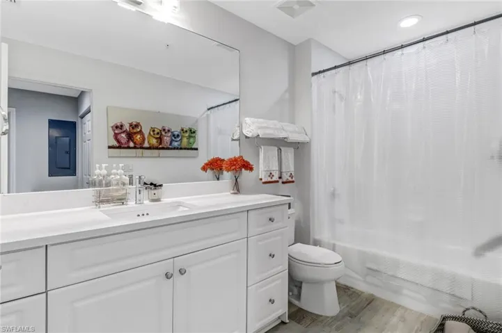 Full bathroom featuring shower / bath combo with shower curtain, hardwood / wood-style flooring, vanity, and toilet