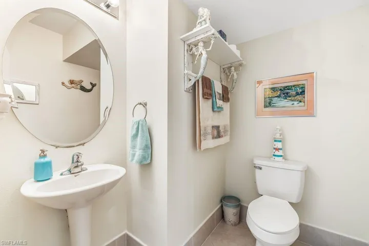 Half guest bathroom with tile patterned flooring, toilet, and pedestal sink