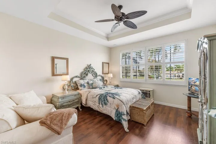 Master Bedroom with a tray ceiling, ornamental molding, LVT flooring, a ceiling fan, and plantation shutters