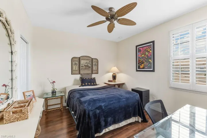 Guest Bedroom featuring LVT flooring, en-suite bath, walk-in closet, plantation shutters, and a ceiling fan