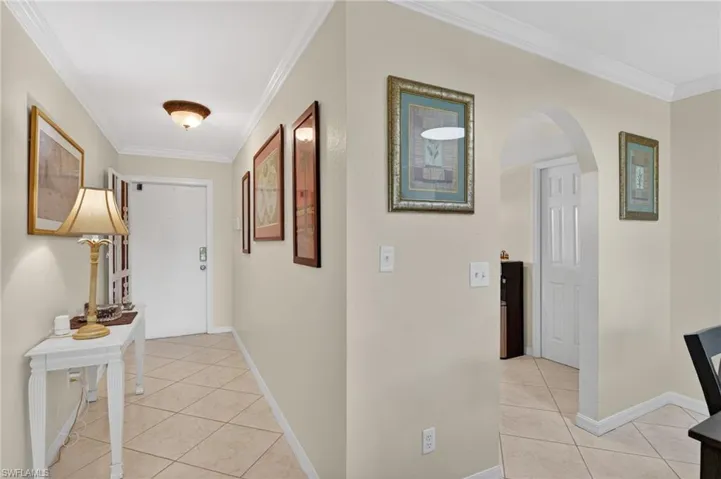 Entryway featuring diagonal tile flooring, crown molding, an arched doorway, and neutral wall tones