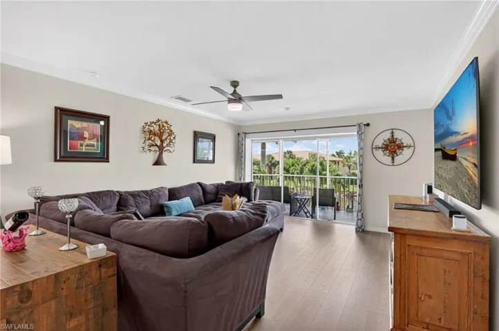 Open-concept living area with wood-finish flooring, crown molding, and a ceiling fan