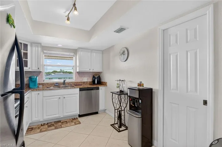 Kitchen featuring white shaker cabinetry, granite-style countertops, stainless steel appliances, and a window with exterior visibility
