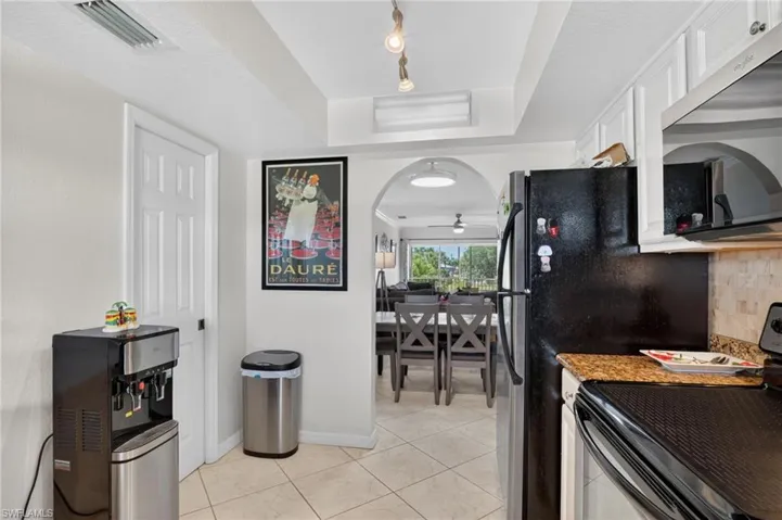 Kitchen featuring white cabinetry, granite-finish countertops, and a tiled backsplash