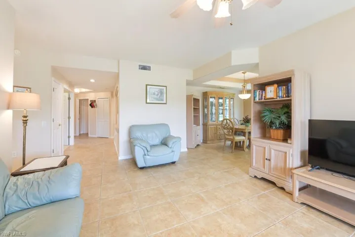 Living room with ceiling fan and light tile flooring