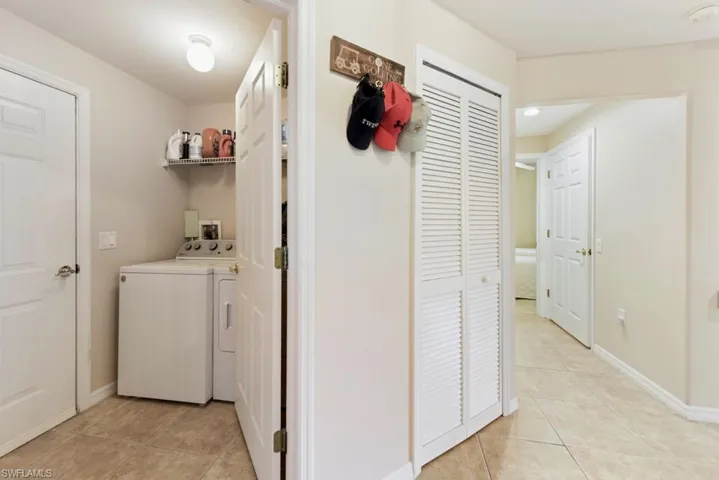 Clothes washing area featuring washing machine and dryer, hookup for a washing machine, and light tile floors