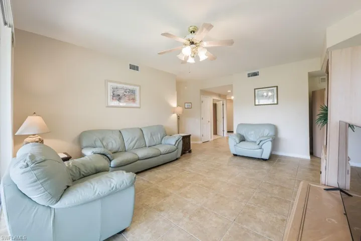 Living room with ceiling fan and light tile floors