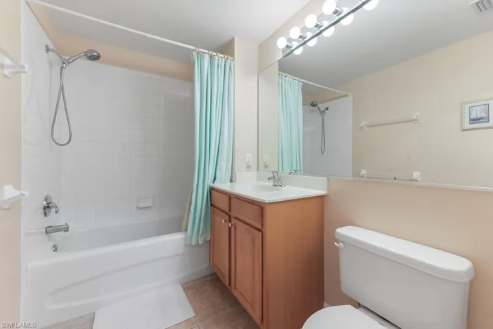 Full bathroom featuring tile flooring, oversized vanity, shower / bath combo with shower curtain, and toilet