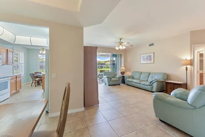 Living room featuring a wealth of natural light, light tile flooring, and ceiling fan