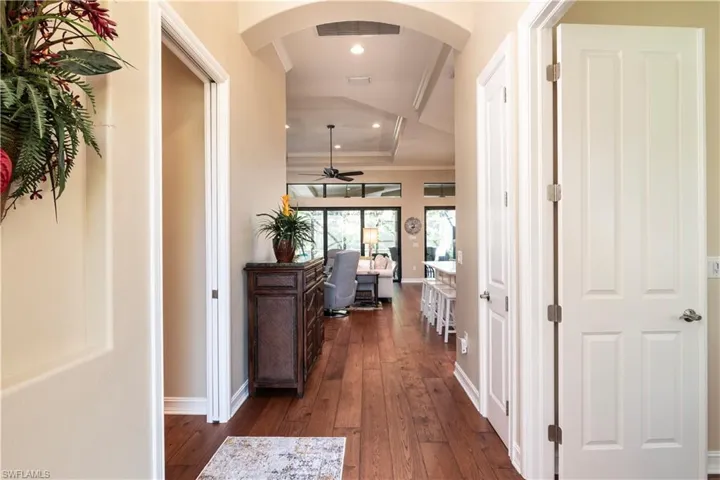 Hallway featuring wood flooring, crown molding, and a tray ceiling