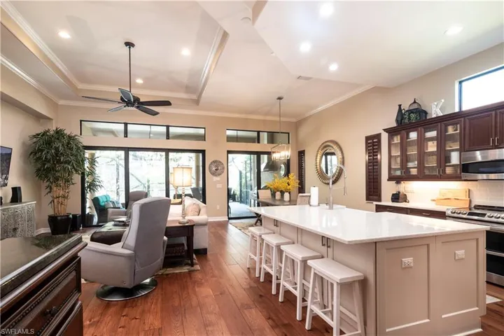 Renovated Kitchen with a one-level center island, extra cabinets, appliances with stainless steel finishes, a kitchen bar, backsplash, and dark wood flooring