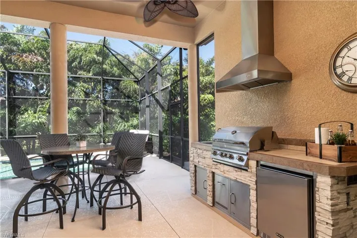 View of patio / terrace featuring an outdoor kitchen, ceiling fan, a grill, and glass enclosure