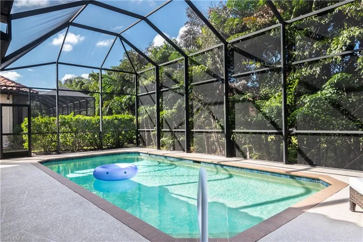 View of swimming pool featuring glass enclosure and a patio