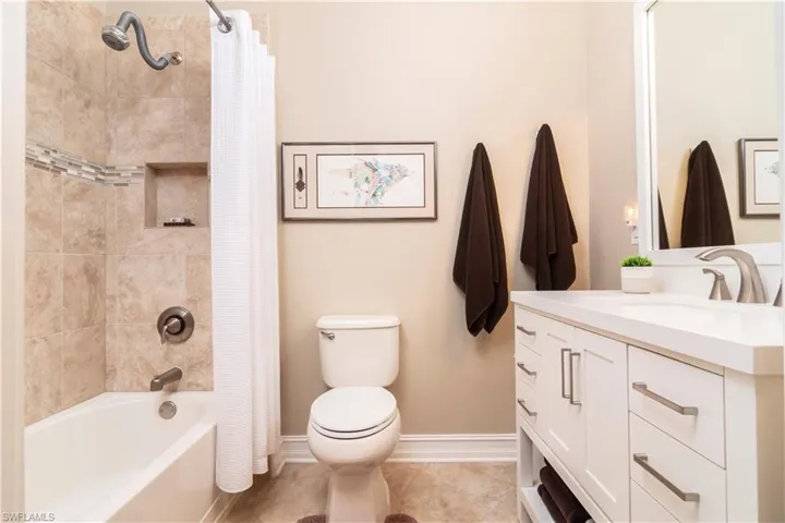 Guest bathroom featuring toilet, vanity, tile patterned flooring, and shower / bathtub combination with curtain