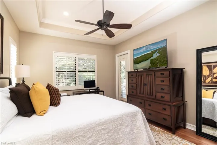 Master Bedroom with hardwood / wood flooring, ceiling fan, and a raised ceiling