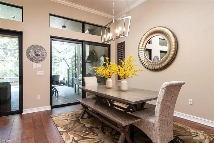 Dining space featuring a chandelier, a healthy amount of sunlight, dark hardwood / wood-style flooring, and crown molding