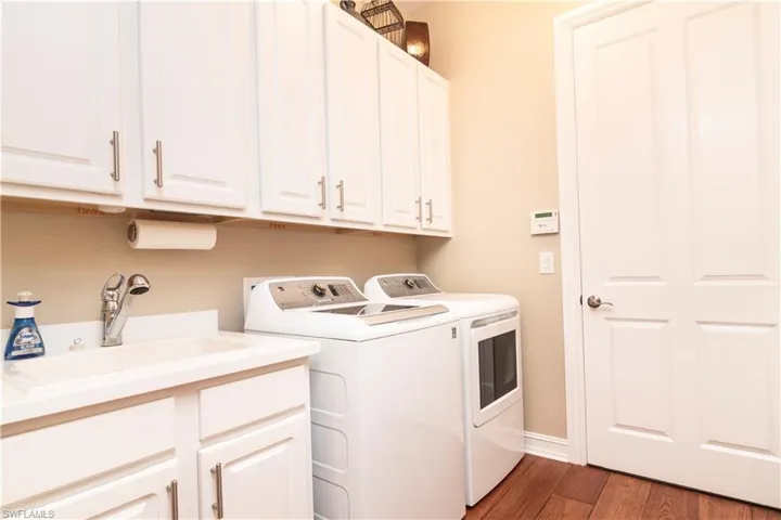 Laundry room featuring cabinets, dark hardwood / wood-style floors, sink, and independent washer and dryer