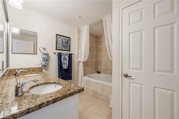 Bathroom with tile patterned floors, vanity, and shower / tub combo with curtain